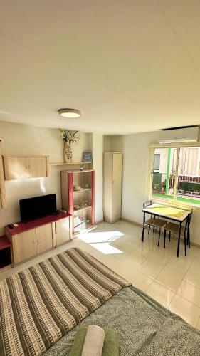una sala de estar con mesa y una habitación con alfombra en Estudio Río Caramel, en Torremolinos