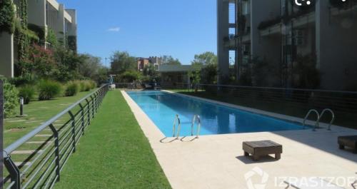 una piscina con un banco junto a un edificio en pilar tortugas departamento premiun en Del Viso