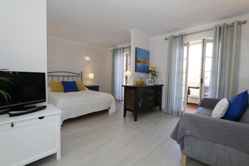 a bedroom with a bed and a tv and a couch at The Old Village, Prestige and Solar by Village 4U in Vilamoura