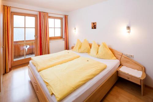 a bedroom with a large bed with yellow sheets and a window at Lederer Zuhaus in Alpbach