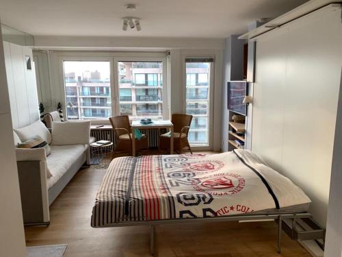 a bedroom with a bed and a living room at Sunny studio with seaview in Knokke-Heist