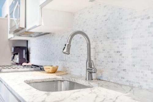 a kitchen with a sink and a white counter top at Stunning Old City 2 Bedroom - Elevator, Bay Windows in Philadelphia