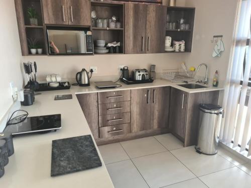 a kitchen with wooden cabinets and white tile floors at 25 On Rooiels in Hartenbos