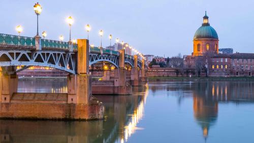 a bridge over a river in front of a building at Appartement de prestige – rue des Arts in Toulouse