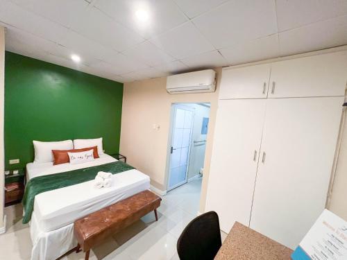 1 dormitorio con cama y pared verde en Stacys Place #4 Studio Apartment en Puerto España