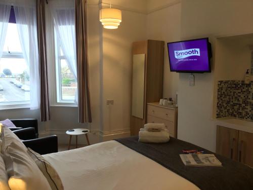 a hotel room with a bed with a tv on the wall at Taunton House in Great Yarmouth