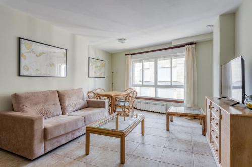ein Wohnzimmer mit einem Sofa und einem Tisch in der Unterkunft Apartamentos Granxola in Sanxenxo