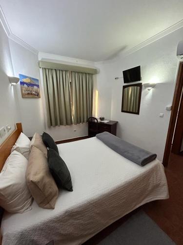 1 dormitorio con 1 cama blanca grande con almohadas en Copacabana Residencial en Costa da Caparica