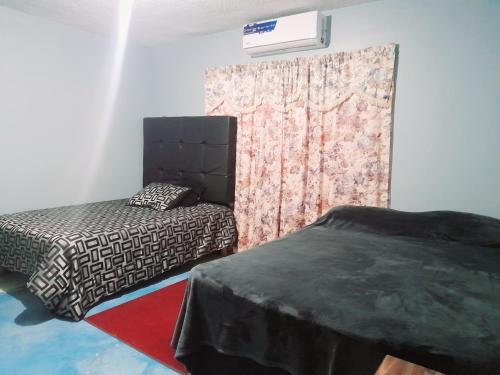 um quarto com 2 camas e uma parede com uma cortina em Casa de hospedaje em Ciudad Juárez