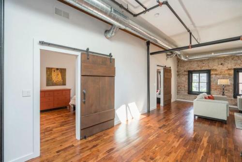 ein offenes Wohnzimmer mit einer Holztür und einer Couch in der Unterkunft PRISTINE 3 BR Million-Dollar Loft Elevator Parking in Philadelphia