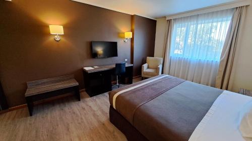 a hotel room with a bed and a desk and a window at Hotel Diego de Almagro Curicó in Curicó