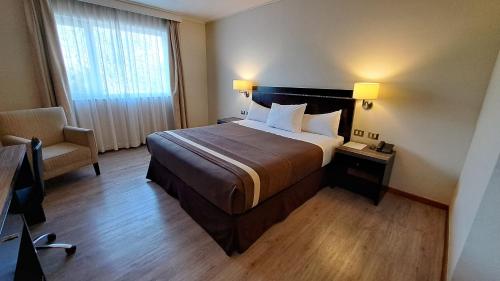 une chambre d'hôtel avec un lit et une chaise dans l'établissement Hotel Diego de Almagro Curicó, à Curicó