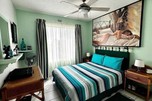 ein Schlafzimmer mit einem Bett mit einem großen Gemälde an der Wand in der Unterkunft Seaview Beachfront Holiday Apartment - 164 Laguna La Crete in Uvongo Beach