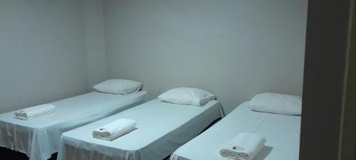 three beds in a room with white walls at Pousada Kit Residence in Brasilia