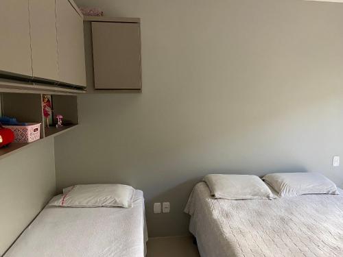 duas camas num quarto com paredes e armários brancos em Loft central Sant Helena Gramado Rs em Gramado
