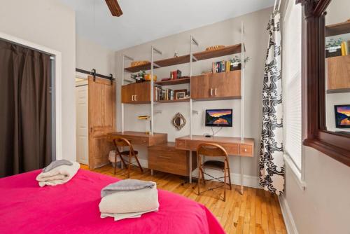 um quarto com uma secretária e uma cama com uma colcha rosa em Fairmount Neighborhood Gem em Filadélfia