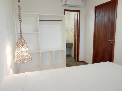 a bedroom with a white bed and a chandelier at Pousada Sal e Sol in São Miguel do Gostoso