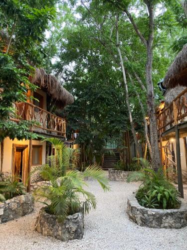 a resort with a building with a balcony and trees at Indajani Hostel Tulum with Pool in Tulum