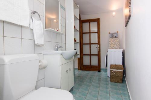 Baño blanco con aseo y lavamanos en Bostani Seaside House Mani en Agios Nikolaos