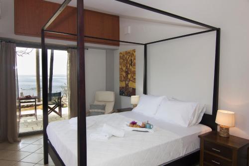 a bedroom with a bed with a view of the ocean at Bostani Seaside House Mani in Agios Nikolaos