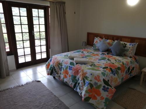 a bedroom with a bed with a floral comforter at Eden Wilds Hawk-in in Port Edward