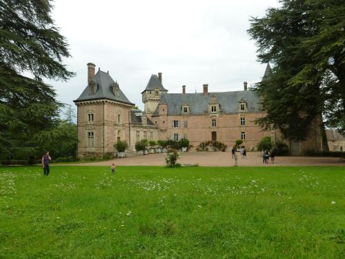 an old castle with people walking in the grass at Chateau de Bresse sur Grosne in Bresse-sur-Grosne