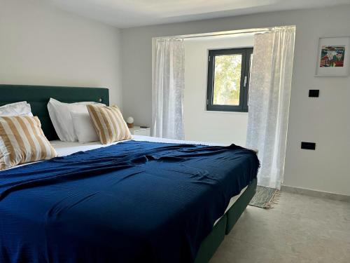 a bedroom with a blue bed with a window at Apartmani Lemona in Šimuni