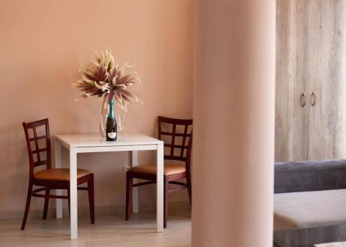 a table and chairs with a vase of flowers on it at Maya Panzio-Rezidencia in Szeged
