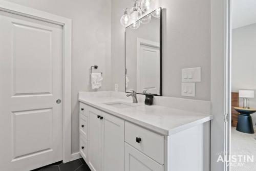 a white bathroom with a sink and a mirror at Enjoy DT Newly Renovated & Patio and Free Swim Club by Austin Vacay in Austin