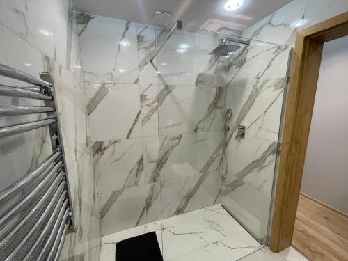 a bathroom with a shower with white marble walls at Mały Książę in Podzamcze