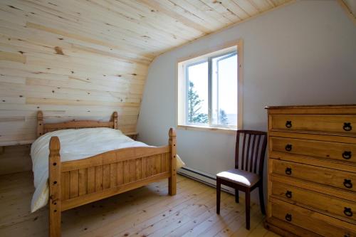 een slaapkamer met een bed, een dressoir en een raam bij Chalets du bout du monde in Gaspé