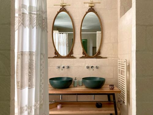 a bathroom with two sinks and two mirrors at Boutique Hotel Masseria Sottomasi in Savelletri di Fasano