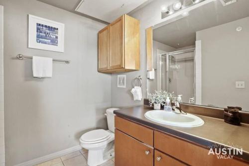 uma casa de banho com um lavatório, um WC e um espelho. em Balcony Skyline View Spiral Staircase Near UT em Austin