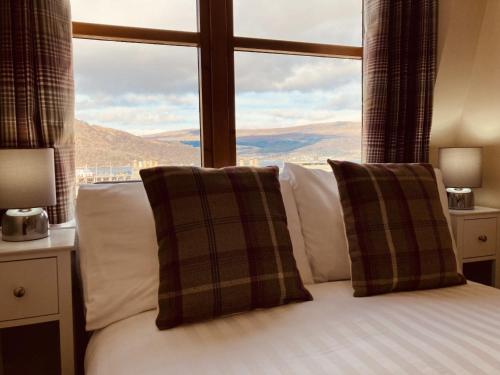 a bed with two pillows in front of a window at The Townhouse in Fort William