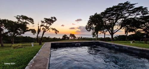 a pool of water with a sunset in the background at Le Domaine de l'Ilet in Saint-Claude