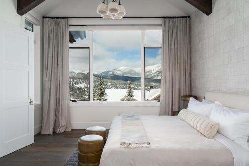 a bedroom with a bed and a large window with snow covered mountains at Inspiration Point Townhome 8C in Big Sky