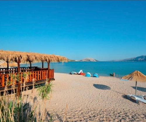 una playa con sillas, sombrillas y agua en Apartments Sweet Dreams, en Zubovići