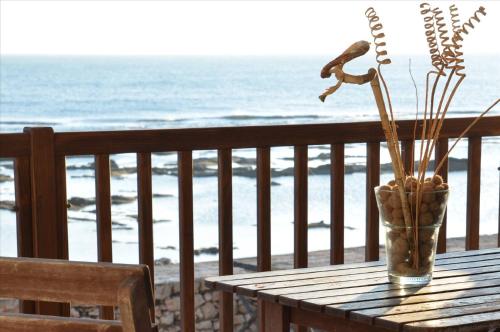 a table with a vase on a balcony with the beach at Oltremare Marzamemi in Marzamemi