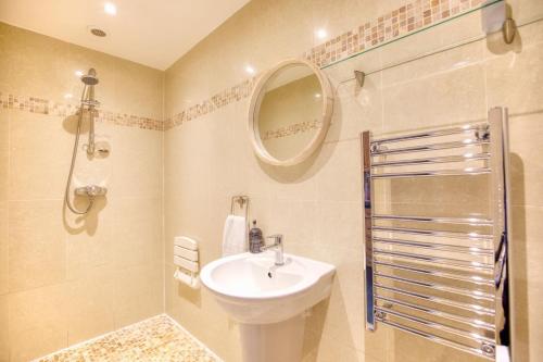 La salle de bains est pourvue d'un lavabo, d'une douche et d'un miroir. dans l'établissement Grindle Cottage, à Woodbury