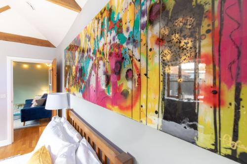 a bedroom with a large colorful painting on the wall at Woodbury Cottage in Woodbury