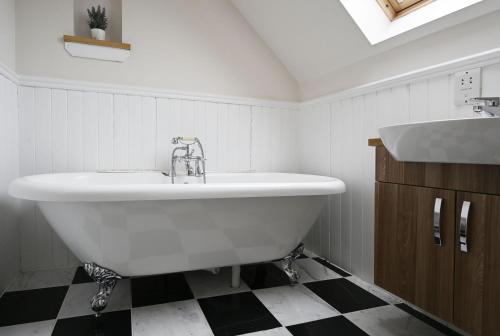 uma casa de banho com uma grande banheira branca e um lavatório. em Sugarloaf em Fort William