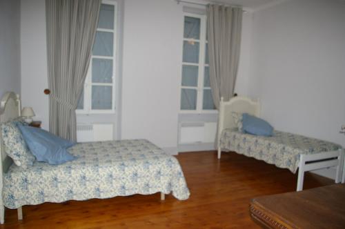 a room with two beds and a table and windows at Grande Maison Mirabelensis - chambres d'hôtes in Mirabel