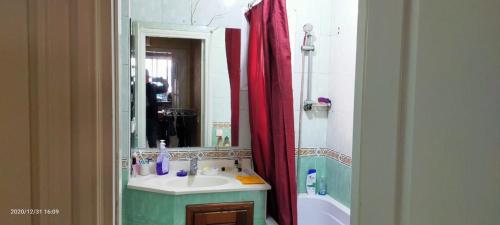 een badkamer met een wastafel, een spiegel en een bad bij APPARTEMENT ARRAJA in Casablanca