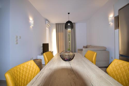 a living room with a wooden table with yellow chairs at Kallixeni Villas in Rethymno Town