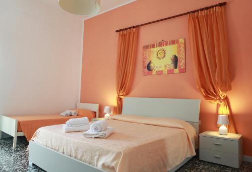 アッリステにあるAppartamenti Blue Houseのベッドルーム1室(オレンジ色のカーテンとタオル付きのベッド2台付)