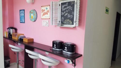 a pink wall with a counter and stools in a room at ALIIKA HOTEL in Albania