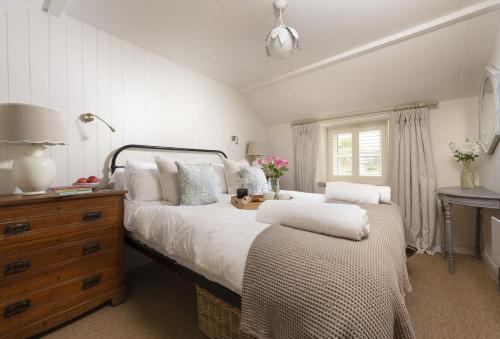 a bedroom with a bed and a dresser and a desk at Pink Cottage in Penzance