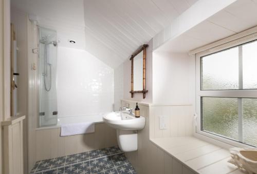 a bathroom with a sink and a toilet and a window at Pink Cottage in Penzance