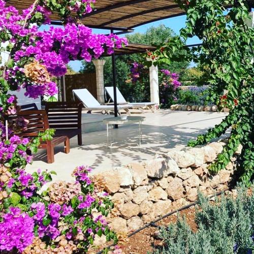 a garden with purple flowers and a stone wall at Boutique Hotel Masseria Sottomasi in Savelletri di Fasano