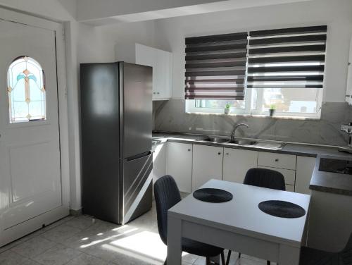a kitchen with a stainless steel refrigerator and a table at Palma Apartment in Faliraki